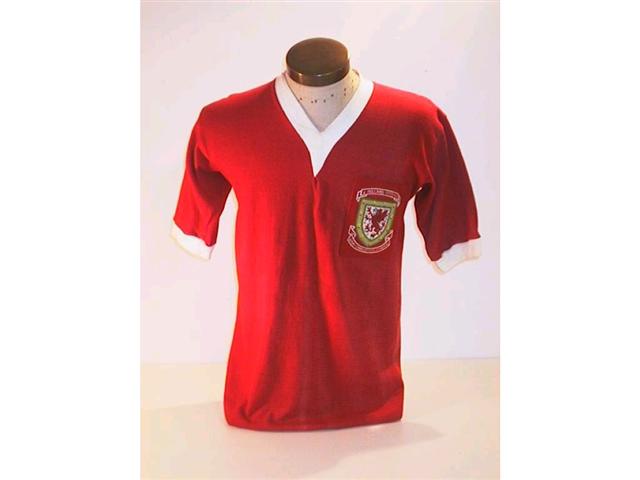457. Wales International Shirt: A red with white trim V-neck shirt with embroidered Welsh crest to front with the match details above, No. 10 to rear. Illus. £500-700